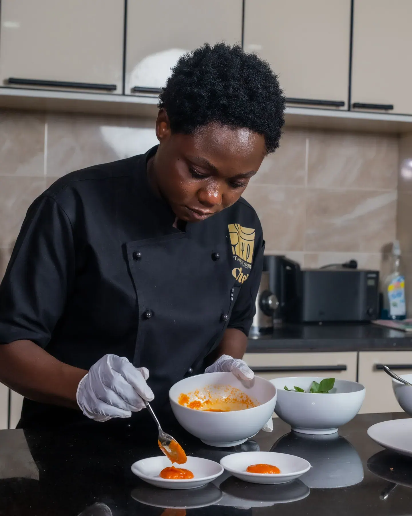 Élève en tenue de cuisine travaillant le dressage d’une assiette