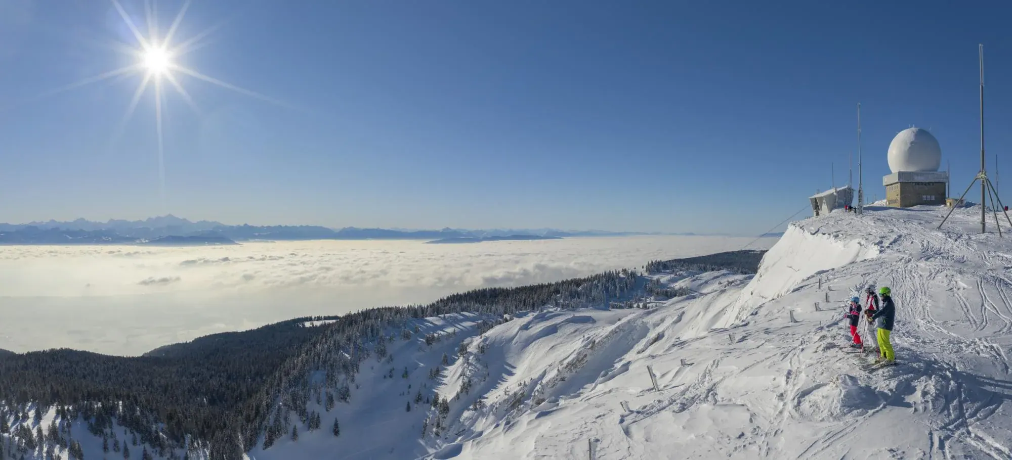Skieurs au sommet de la Dôle face au panorama enneigé